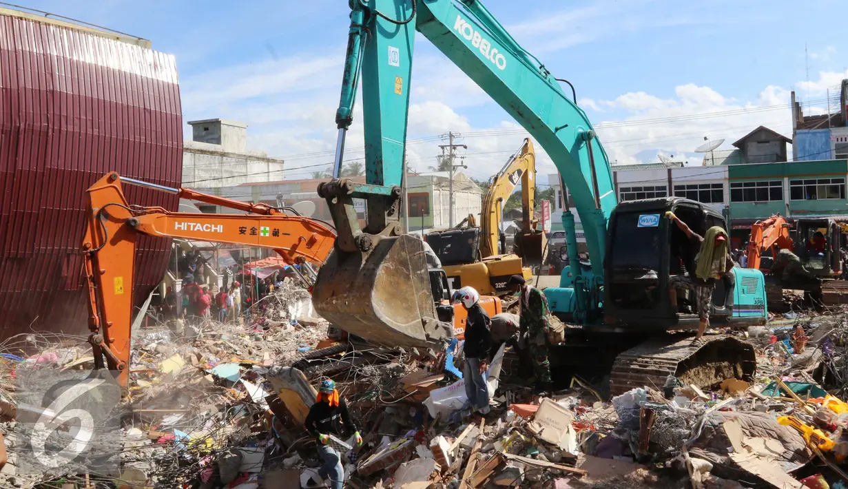 Eskavator membantu mengangkat puing bangunan yang runtuh akibat gempa di Pasar Meureudu, Pidie Jaya, Aceh, Kamis (8/12). Dikabarkan korban meninggal sudah mencapai 102 orang. (Liputan6.com/Angga Yuniar)