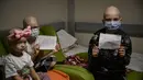 Anak-anak yang berjuang dengan kanker memegang kertas bertuliskan "Hentikan Perang" di shelter bom yang terletak di ruang bawah tanah pusat onkologi di Kiev, Senin (28/2/2022). Tentara Rusia mengatakan, warga sipil Ukraina dapat meninggalkan ibu kota Kiev dengan bebas. (Aris Messinis / AFP)