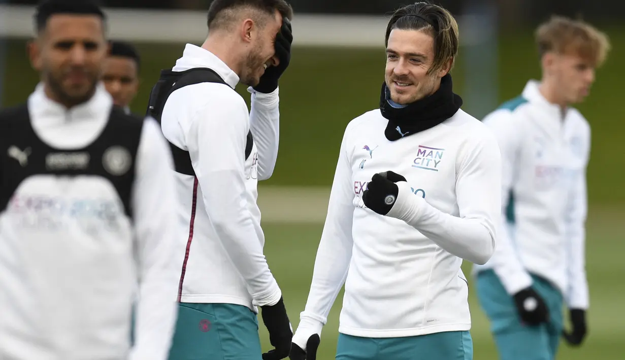 <p>Gelandang Manchester City, Jack Grealish (kiri) berbicara dengan bek Aymeric Laporte saat mengambil bagian dalam sesi latihan di tempat latihan Manchester City di Manchester, barat laut Inggris, pada 25 April 2022. Manchester City akan bertanding melawan Real Madrid pada leg pertama semifinal Liga Champions. (AFP/Oli Scarff)</p>