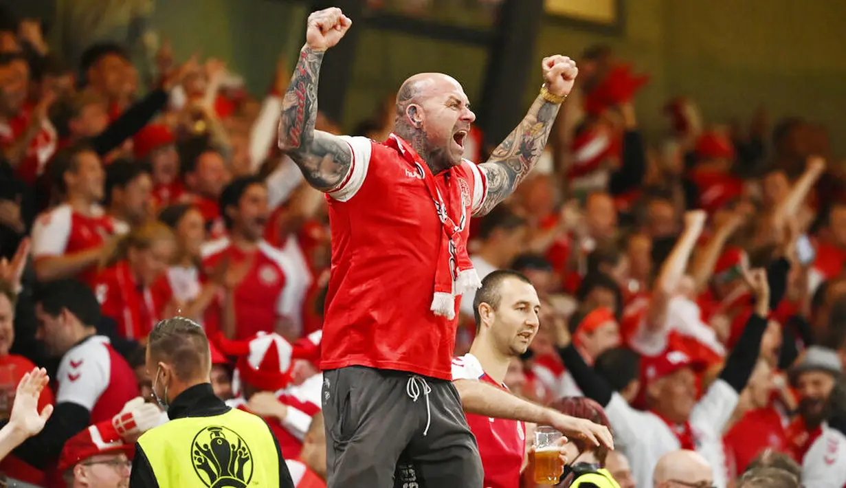 Sorang suporter Denmark dengan menggebu-gebu merayakan kesuksesan Tim Dinamit yang secara dramatis lolos ke babak 16 besar Euro 2020. (Jonathan Nackstrand/Pool via AP)