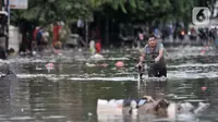 Warga menuntun sepeda saat melintasi banjir yang merendam Jalan RA Kartini, Bekasi, Jawa Barat, Kamis (2/1/2020). Banjir yang merendam Jalan RA Kartini sejak kemarin melumpuhkan akses kendaraan dan perekonomian warga setempat. (merdeka.com/Iqbal Nugroho)