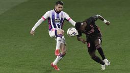Pemain Real Valladolid, Luis Perez, berebut bola dengan pemain Real Madrid, Vinicius Junior, pada laga Liga Spanyol di Stadion Jose Zorrila, Minggu (21/2/2021). Real Madrid menang dengan skor 1-0. (AP/Alvaro Barrientos)