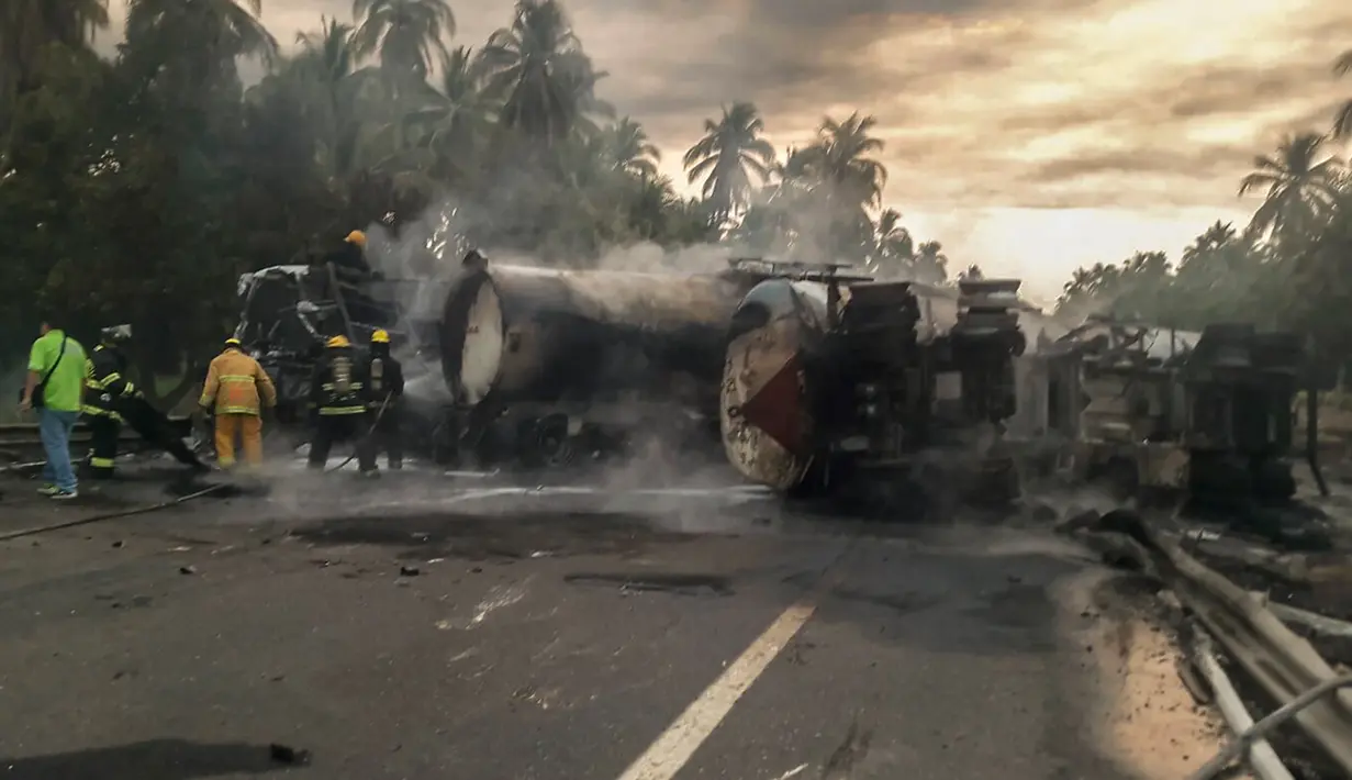 Petugas berusaha memadamkan api yang masih tersisa akibat tabrakan antara sebuah bus dengan truk tangki bahan bakar (BBM) di negara bagian Guerrero, Meksiko, Kamis (14/4). Penyebab tabrakan belum diketahui secara pasti. (HO/Guerrero Civil Protection/AFP)