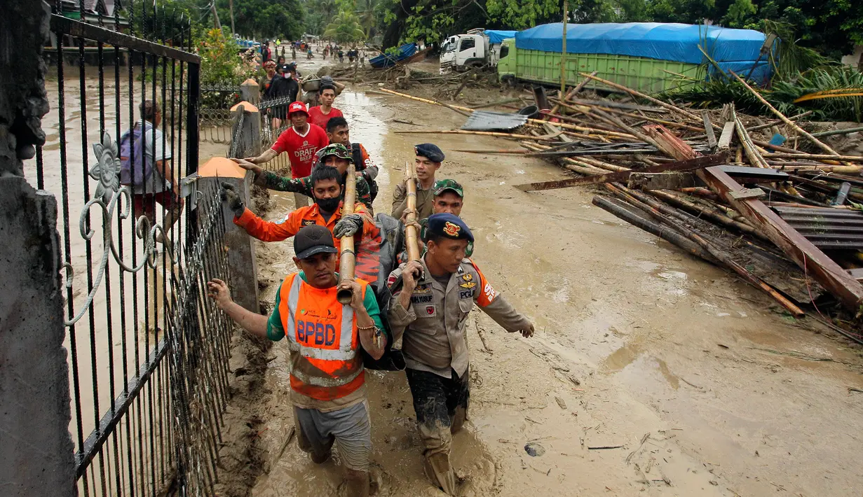 Tim penyelamat membawa mayat korban setelah banjir bandang di desa Radda di Kabupaten Luwu Utara, Sulawesi Selatan (14/7/2020). Lebih dari 4.000 keluarga terdampak akibat kejadian tersebut. (AP Photo)
