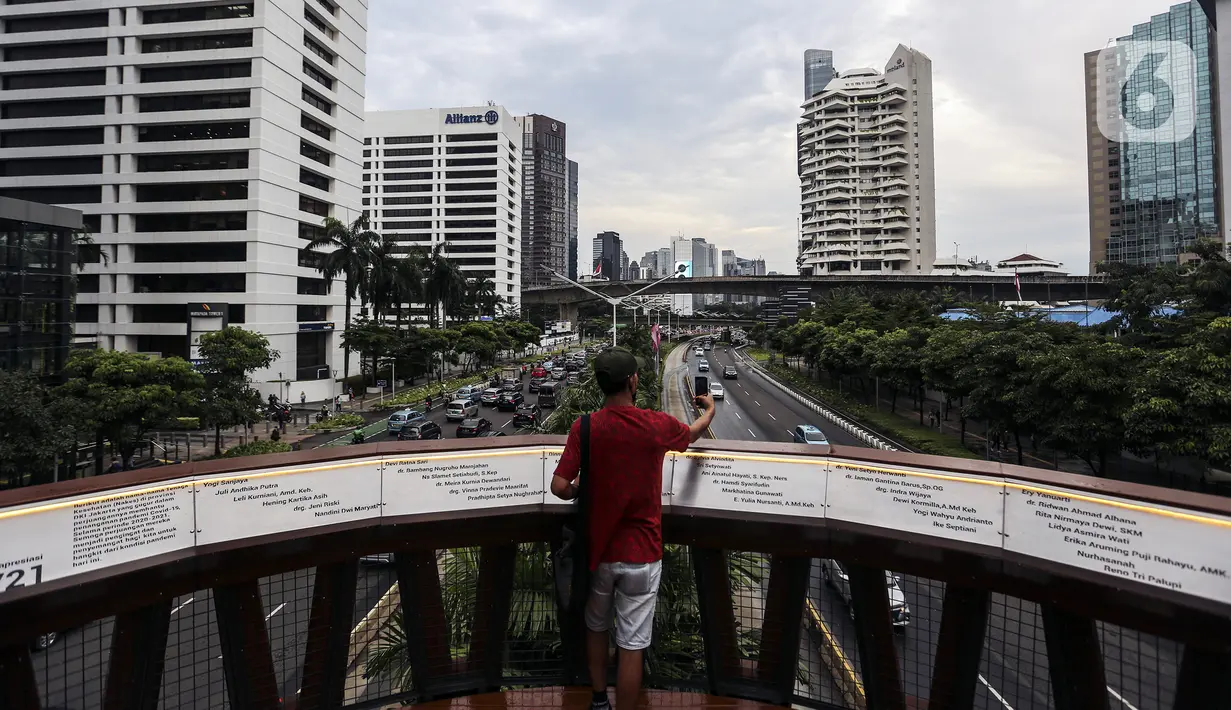 Warga berswafoto dengan kamera ponsel di Jembatan Penyeberangan Orang (JPO) Pinisi, Jalan Jenderal Sudirman, Karet, Jakarta, Selasa (15/3/2022). Keberadaan JPO Pinisi langsung disambut baik oleh warga dengan ramai-ramai berkunjung untuk sekadar melakukan swafoto. (Liputan6.com/Johan Tallo)