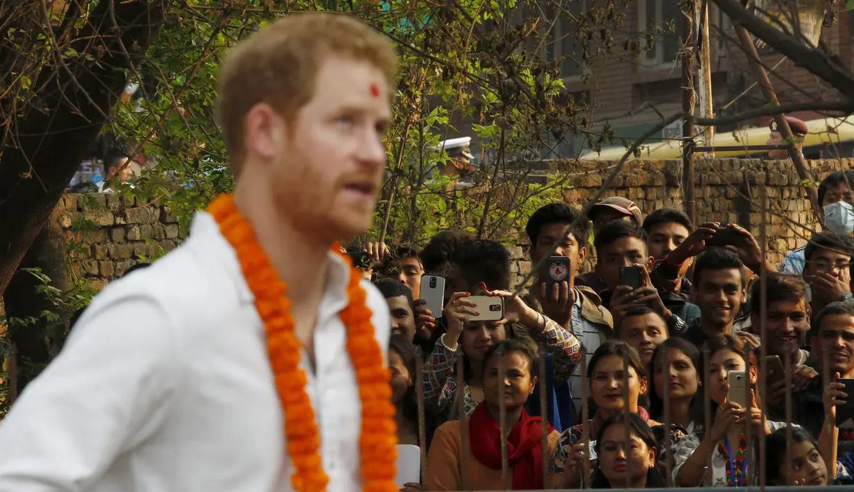 Warga berkumpul saat Putra Mahkota Kerajaan Inggris, Pangeran Harry sedang mengamati situs warisan dunia, Patan Durbar Square yang turut terkena dampak gempa tahun lalu, di Kathmandu, Nepal, Minggu (20/3). (REUTERS/Prakash Mathema/Pool)