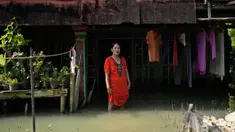 Zuriah berdiri di luar rumahnya yang terendam banjir di Mondoliko, Jawa Tengah, Indonesia, 1 Agustus 2022. Karena tidak mampu untuk pindah ke rumah baru, Zuriah tetap tinggal di rumah itu meski hampir semua tetangganya pindah. (AP Photo/Dita Alangkara)