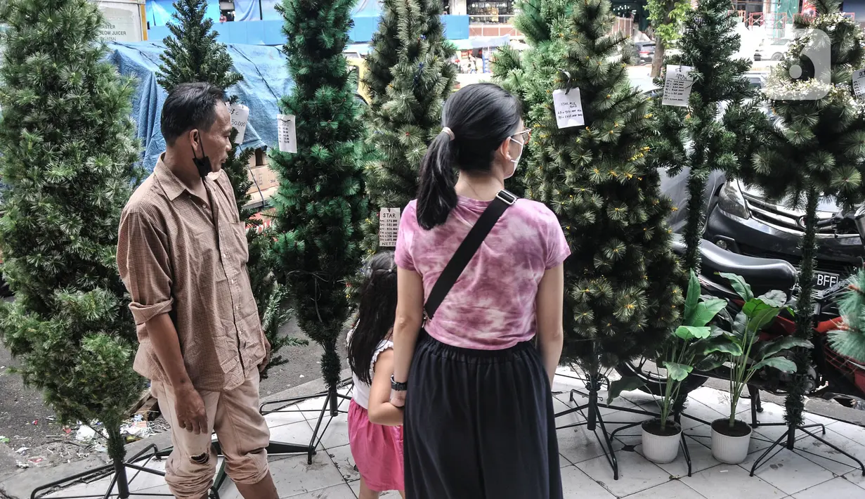 Pengunjung memilih pohon Natal di salah satu toko di Pasar Asemka, Jakarta, Senin (12/12/2022). Penjualan pernak-pernik Natal di Pasar Asemka mengalami peningkatan. (merdeka.com/Iqbal S. Nugroho)