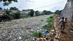 Warga melintas di pinggir Kali Pisang Batu yang dipenuhi sampah, Tarumajaya, Bekasi, Rabu (9/1). Tumpukan sampah tersebut berasal dari limbah rumah tangga. (Merdeka.com/Iqbal S Nugroho)