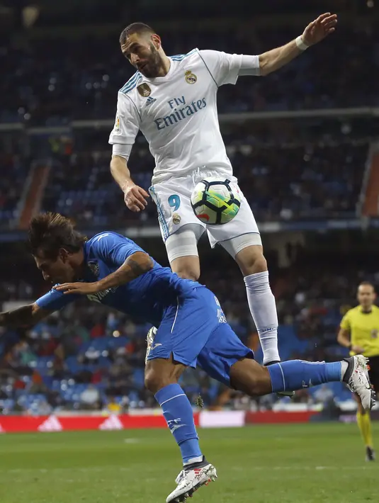 Duel pemain Real Madrid, Karim Benzema (atas) dan pemain Getafe, Damian Suarez pada lanjutan La Liga Santander di Santiago Bernabeu stadium, Madrid, (3/3/2018). Real madrid menang 3-1. (AP/Francisco Seco)