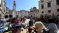 Wisatawan duduk di teras Stradun, jalan utama kota tua Dubrovnik pada 28 Maret 2019. Tahun lalu lebih dari 1,2 juta turis mengunjungi Dubrovnik, kota yang paling banyak dikunjungi di Kroasia. (Denis LOVROVIC / AFP)