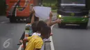 Sejumlah anak menggunakan kertas meminta bunyi klakson telolet ke bus yang lewat di jalan raya A Yani Surakarta, Solo, Kamis (22/12). Fenomena ini mendunia setelah beberapa artis dan tokoh terkenal dunia berkomentar di media sosial. (Liputan6.com/Gholib)