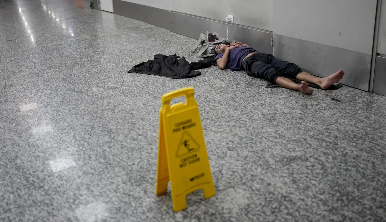 <p>Saat penumpang dan staf mulai berdatangan di pagi hari, puluhan orang masih tidur, sebagian di kursi dan sebagian lagi di lantai. (AP Photo/Natacha Pisarenko)</p>