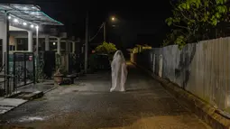 Urabil Alias, 38, mengenakan kostum hantu saat berjalan di daerah perumahan selama aturan pembatasan gerakan atau Movement Control Order di Terengganu, Malaysia, 16 April 2020. Aksi pria itu untuk menakuti warga agar tidak keluar dari rumah selama lockdown akibat virus corona. (Mohd RASFAN/AFP)