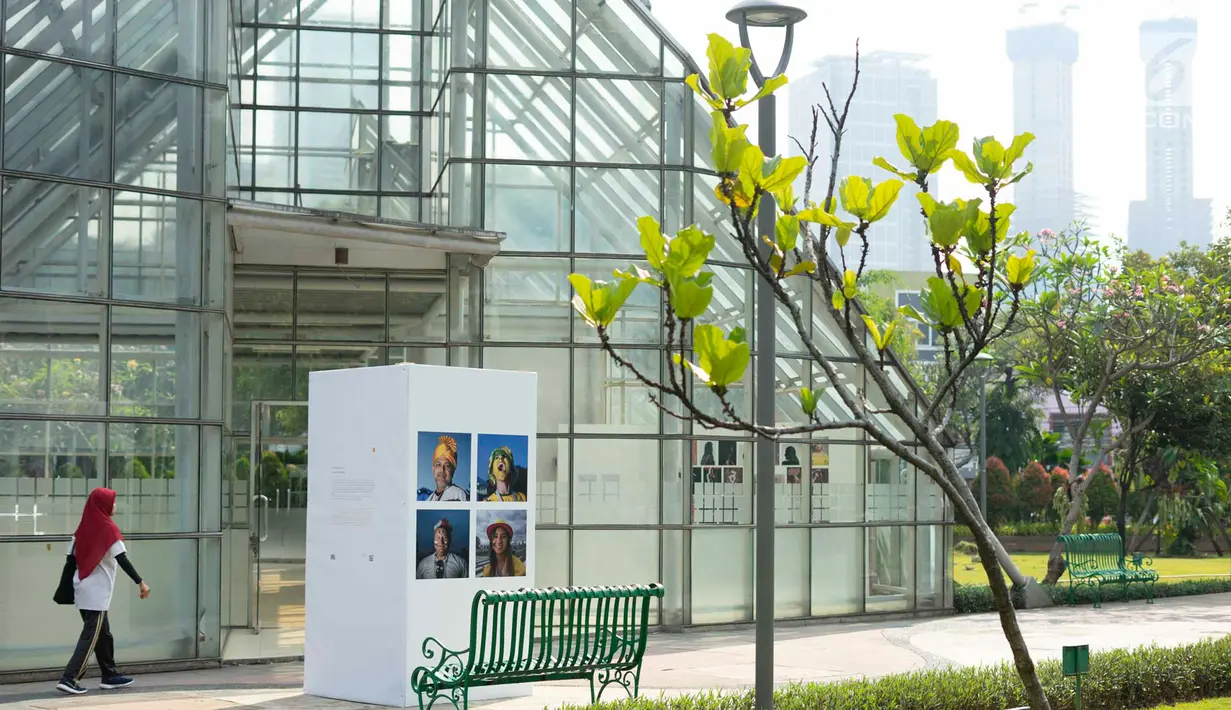Pejalan kaki berjalan dekat foto yang dipajang dalam pameran bertajuk 'Identitas' pada acara Jakarta International Photo Festival (JIPFest) 2019 di Taman Menteng, Jakarta, Rabu (3/7/2019). JIPFest 2019 berlangsung pada 25 Juni hingga 9 Juli 2019. (Liputan6.com/Immanuel Antonius)