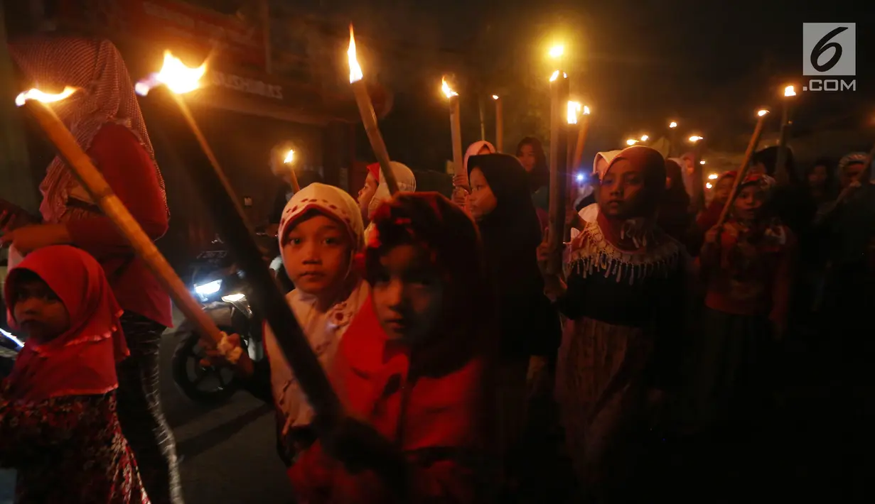 Sejumlah anak berpawai sambil membawa obor di Jalan Tengah, Batu Ampar, Jakarta Timur, Sabtu (24/6). Kegiatan tersebut dalam rangka menyambut Idul Fitri 1 Syawal 1438 Hijriyah. (Liputan6.com/Angga Yuniar)