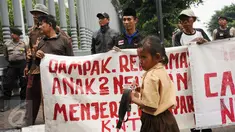 Seorang anak melintas di depan pengunjuk rasa di Kedubes Belanda di Jakarta, Rabu (23/11). Mereka meminta pemerintah Belanda menghentikan upaya mendorong investasi dalam pembangunan infrastruktur di Teluk Jakarta. (Liputan6.com/Helmi Fithriansyah)