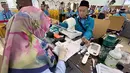 Setibanya di lokasi, para jemaah langsung menjalani proses pemeriksaan kesehatan, penyelesaian administrasi, serta penguatan manasik haji dan sosialisasi kesehatan. Tampak dalam foto, petugas memeriksa kesehatan calon haji setibanya di Asrama Haji Pondok Gede, Jakarta, Selasa (21/4/2026). (merdeka.com/Arie Basuki)