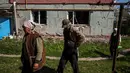 <p>Orang-orang berjalan untuk menerima bantuan kemanusiaan, di tengah invasi Rusia ke Ukraina, di desa Vilkhivka, dekat kota timur Kharkiv, pada 14 Mei 2022. Puluhan rumah di Vilkhivka, sebuah desa berpenduduk sekitar 2.000 jiwa, hancur oleh peluru, ledakan atau kebakaran. Puing-puing berserakan di jalan-jalan termasuk selongsong peluru, dan sisa-sisa amunisi. (Dimitar DILKOFF / AFP)</p>