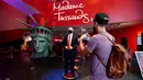 Pengunjung menganbil foto sosok Donald Trump yang bermasker saat Madame Tussauds New York dibuka kembali di New York City, Kamis (27/8/2020). Patung lilin Donald Trump akan berada di pintu masuk untuk mengingatkan tentang protokol kesehatan, termasuk pemakaian masker (Cindy Ord/Getty Images/AFP)