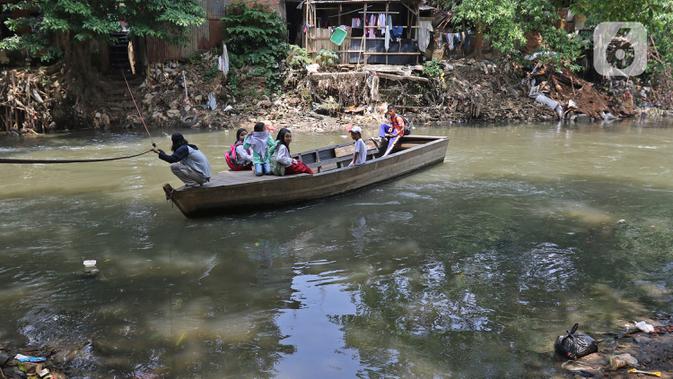 Sejumlah murid SD naik perahu di Sungai Ciliwung, Kampung Tanah Rendah, Jakarta, Jumat (15/11/2019). Pembataalan pembebasan 118 bidang tanah tersebut menyebabkan proyek normalisasi Sungai Ciliwung yang telah berhenti sejak tiga tahun yang lalu menjadi terhambat. (Liputan6.com/Herman Zakharia)