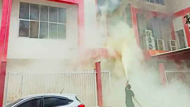 Petugas berusaha memadamkan api di gedung Telkomsel Pekanbaru yang terbakar.