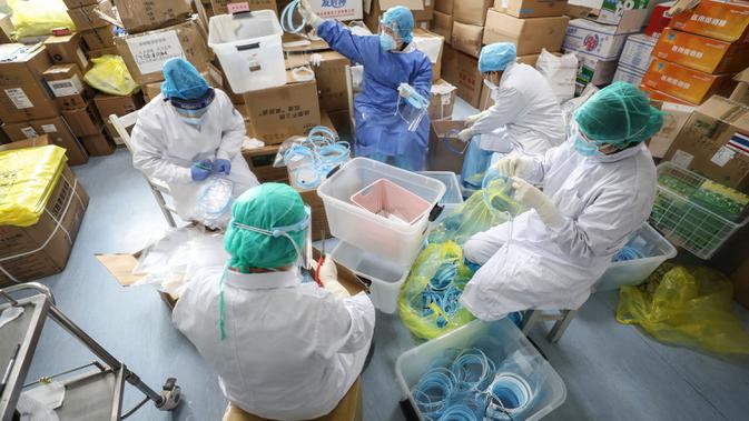 Petugas medis memasang topeng pelindung di Rumah Sakit Palang Merah di Wuhan, 28 Februari 2020. Virus Corona yang bermula di China tengah pada Desember 2019 kini menyebar secara global di mana lima negara terdampak paling besar, yakni Cina daratan, Korea Selatan, Iran, Italia dan Jepang (STR/AFP)