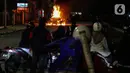 Warga menyaksikan sebuah mobil terbakar di Jalan Asia Afrika, Jakarta, Kamis (18/3/2021) dinihari. Diduga penyebab api adalah akibat dari hubungan pendek arus listrik yang terjadi di bagian mesin. (Liputan6.com/Johan Tallo)