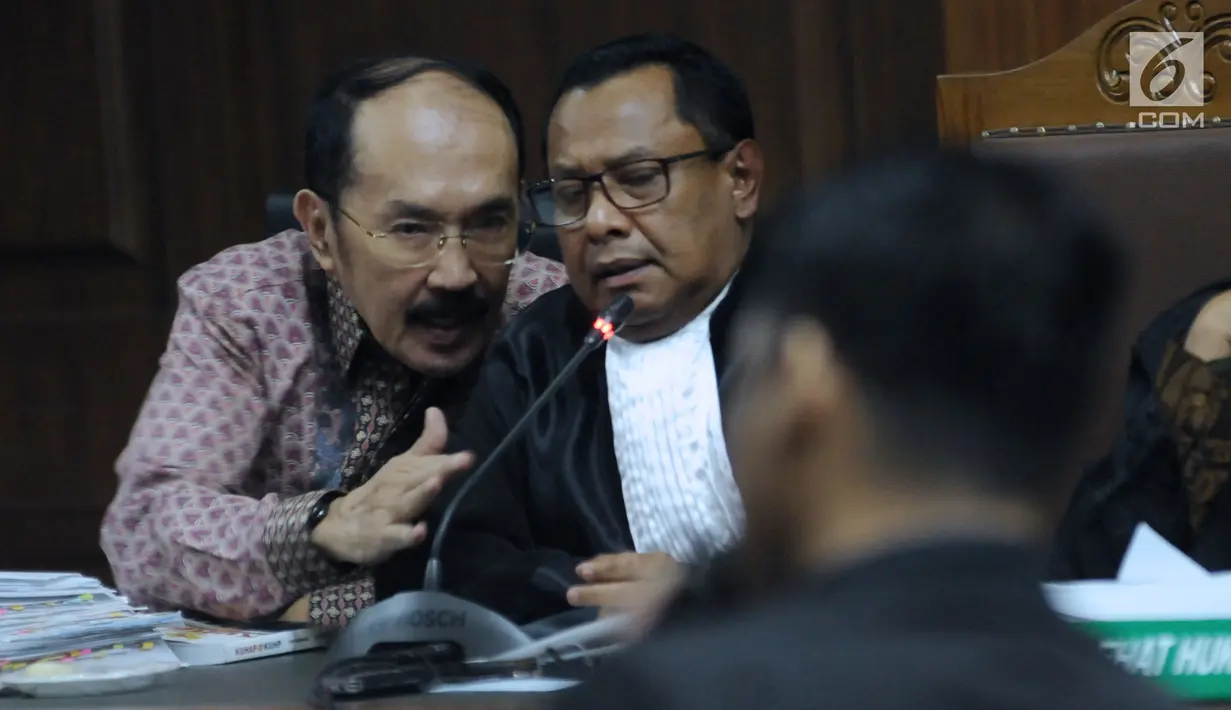 Terdakwa kasus merintangi penyidikan dugaan korupsi e-KTP, Fredrich Yunadi (kiri) berbincang dengan penasehat hukumnya pada sidang lanjutan di Pengadilan Tipikor, Jakarta, Kamis (12/4). Sidang mendengar keterangan saksi. (Liputan6.com/Helmi Fithriansyah)