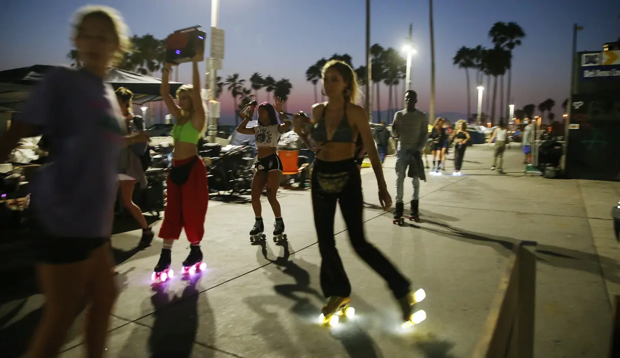 Orang-orang bermain sepatu roda di sepanjang trotoar Venice Beach di Venice, California, Kamis (3/9/2020). Menurut data Google, pencarian terkait sepatu roda dari Maret hingga Mei di Amerika Serikat meningkat hampir empat kali lipat. (Mario Tama/Getty Images/AFP)