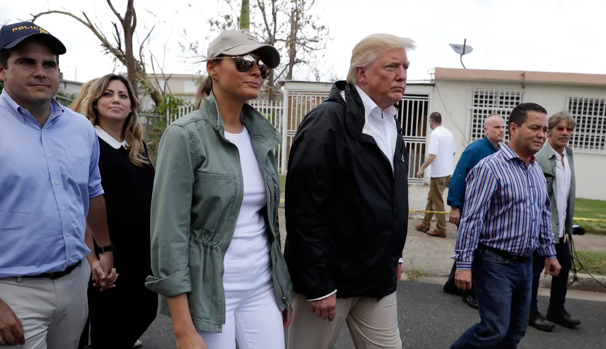 Presiden AS Donald Trump dan ibu negara Melania Trump ditemani Gubernur Puerto Rico, Ricardo Ricardo Rosselló berkeliling ke permukiman warga di Guaynabo, Selasa (3/10). Trump meninjau kerusakan yang diakibatkan Badai Maria dua pekan lalu. (AP/Evan Vucci)