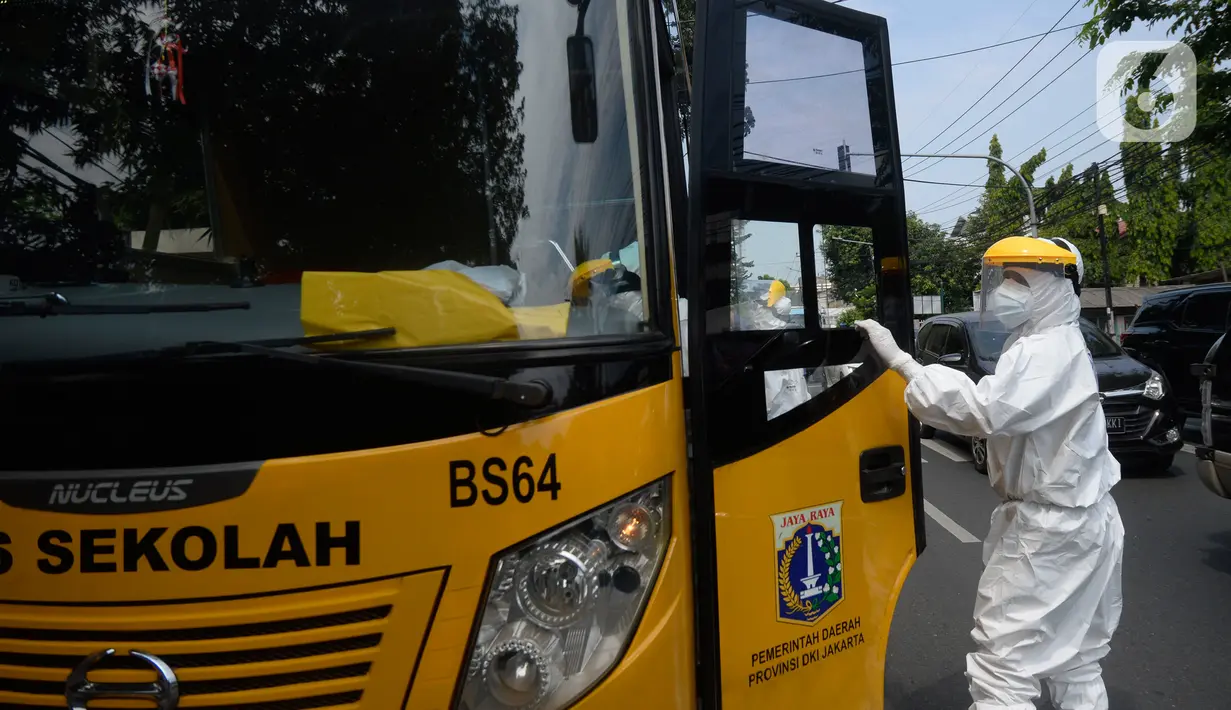 Petugas Dishub memakai baju APD akan menjemput korban yang diduga terjangkit Covid-19 menggunakan bus sekolah di Puskesmas Kebayuran Lama, Jakarta, Senin (6/7/2020). Bus sekolah tersebut selama liburan dibantukan untuk mengangkut pasien Covid-19 ke Wisma Atlet Kemayoran. (merdeka.com/Dwi Narwoko)