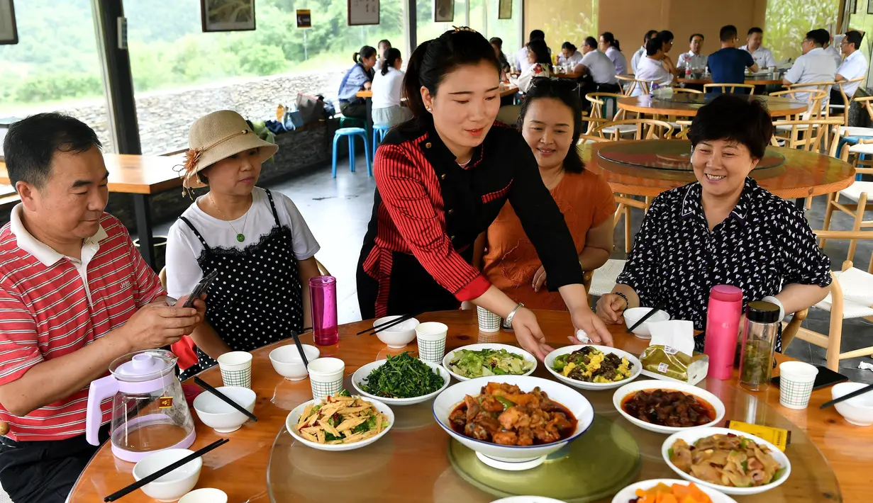 Para wisatawan menyantap makan siang di sebuah lokasi wisata peternakan (farm stay) di Desa Baiyun, Wilayah Taibai, Provinsi Shaanxi, China barat laut (5/7/2020). (Xinhua/Liu Xiao)