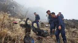 Petugas memeriksa jasad tubuh yang terbakar di dekat jatuhnya pesawat Twin Otter milik maskapai Tara Air di pegunungan Nepal, Rabu (24/2). Di sekitar puing pesawat juga ditemukan potongan tubuh yang diduga milik para penumpang. (REUTERS/Santosh Gautam)