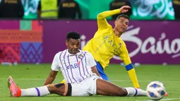 Pemain Al-Nassr, Cristiano Ronaldo, berusaha melewati pemain Al-Ain, Saeed Juma, di Liga Champions Asia 2023/2024 di Al-Awal Park Stadium, Selasa (12/3/2024). (AFP/Fayez Nureldine)