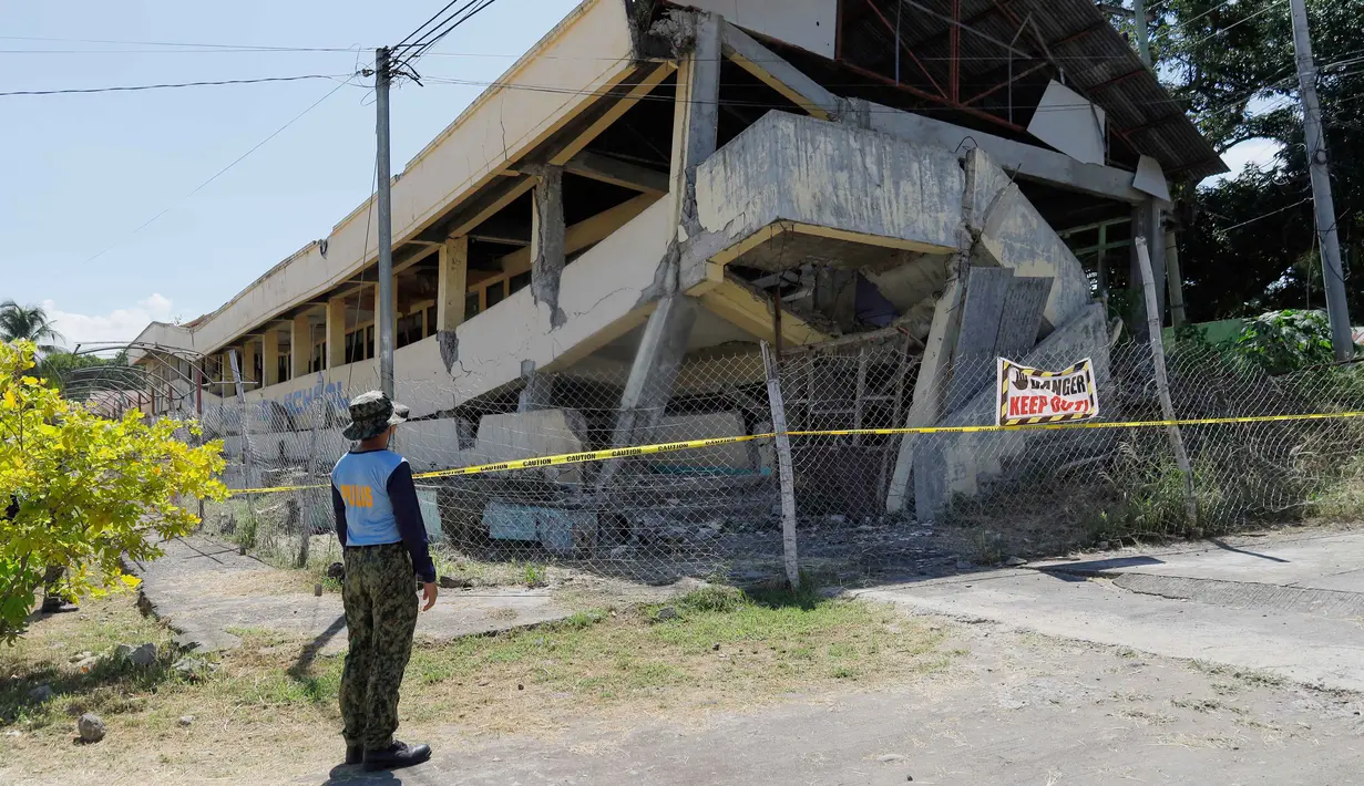 Seorang polisi melihat sebuah bangunan terbengkalai yang runtuh pasca gempa bumi melanda Matanao, provinsi Davao del Sur, Filipina, Senin 8 Juni 2026. (AP Photo/Nycel Basillote)