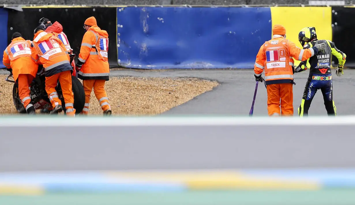Pembalap Monster Energy Yamaha, Valentino Rossi, dibantu keluar arena usai terjatuh pada balapan MotoGP Prancis di Le Mans, Minggu (11/10/2020). Petrucci finis pertama dengan catatan waktu 45 menit 54,736 detik. (AP Photo/David Vincent)