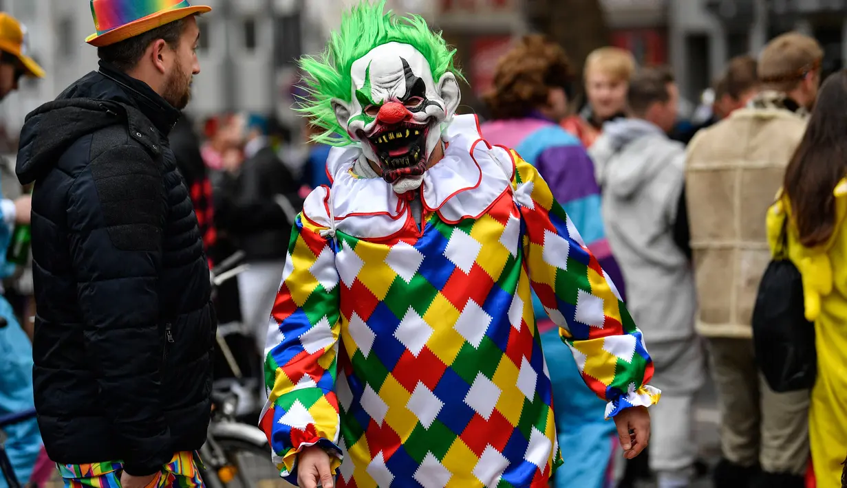Seorang pria dengan mengenakan kostum Horror Clown berjalan saat puluhan ribu orang bersuka ria merayakan dimulainya musim karnaval di jalan-jalan Kota Cologne, Jerman, Senin (11/11/2019). Karnaval ini akan mencapai puncaknya pada bulan Februari 2020. (AP Photo/Martin Meissner)