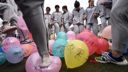 Para siswa menginjak-injak balon melepaskan stres sebelum ujian masuk perguruan tinggi di sebuah sekolah tinggi di Handan, Provinsi Hebei China utara, (24/5). Cara unik ini dilakukan agar para siswanya lebih rileks menghadapi ujian. (AFP PHOTO/STR)