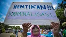 Seorang nenek membawa tulisan ‘Hentikan Kriminalisasi’ saat melakukan aksi Karnaval Rakyat Lawan Korupsi dari patung kuda menuju Istana Negara, Jakarta, Rabu (8/4/2015). (Liputan6.com/Faizal Fanani)