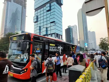 Warga menaiki angkutan umum di tepi Jalan Jenderal Sudirman, Jakarta, Senin (8/7/2019). Tidak adanya halte menyebabkan warga terpaksa menunggu angkutan umum di tempat seadanya. (Liputan6.com/Immanuel Antonius)