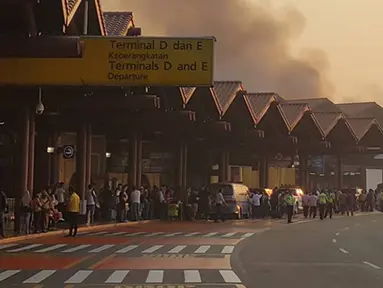 Sejumlah penumpang melihat kebakaran yang terjadi di Terminal 2E di Bandara Soekarno Hatta, Jakarta, Minggu (5/7/2015).  Kebakaran di Terminal 2E ini membuat panik ribuan penumpang yang sedang menunggu jadwal penerbangan. (Twitter@avgustin88)