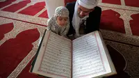 Pria Muslim mendengarkan ketika seorang anak membaca Al-qur'an pada hari pertama bulan suci Ramadhan di Masjid Al-Kabir di kota tua Sanaa, ibu kota Yaman, 2 April 2022. Pada bulan Ramadhan umat muslim memanfaatkan waktu untuk memperbanyak ibadah dengan membaca Al Quran. (MOHAMMED HUWAIS/AFP)