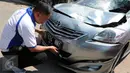 Petugas kepolisian menunjukkan plat mobil yang menabrak pejalan kaki di Jalan Boulevard Artha Gading, Jakarta, Sabtu (9/1/2016). Akibat kejadian tersebut, satu pengendara sepeda dan satu pejalan kaki meninggal di lokasi. (Liputan6.com/Helmi Afandi)