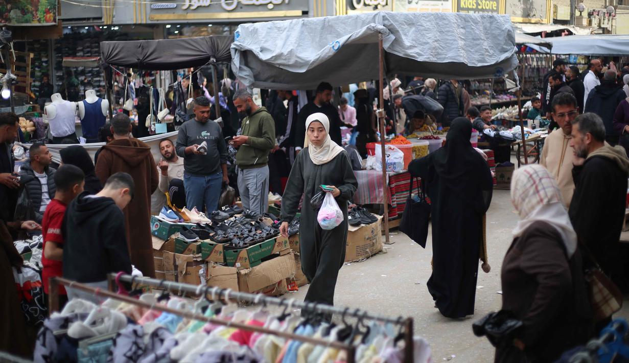 Warga Palestina yang mengungsi berbelanja di kios-kios pasar jalanan sekitar kamp pengungsi Nuseirat, Jalur Gaza tengah, pada Rabu 18 Maret 2026. Meski berada dalam situasi sulit dan di tengah reruntuhan, pasar jalanan sekitar kamp pengungsi Nuseirat, Jalur Gaza tengah, tetap ramai dikunjungi warga Palestina yang mengungsi. (Eyad Baba/AFP)