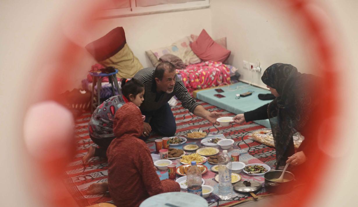 Lonjakan pengungsian itu terjadi hanya dalam beberapa hari sejak pertempuran kembali pecah di wilayah Lebanon. Tampak dalam foto, seorang wanita pengungsi yang tinggal bersama keluarganya di ruang kelas sekolah, setelah melarikan diri dari serangan udara Israel di pinggiran selatan Beirut, Lebanon, duduk untuk berbuka puasa bersama, pada 7 Maret 2026. (Ibrahim AMRO/AFP)