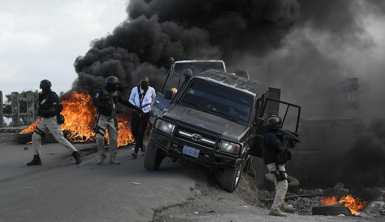 Polisi meninggalkan kendaraan mereka saat demonstrasi yang berubah menjadi kekerasan di Cap-Haitien, Haiti, Kamis (22/7/2021). Demonstrasi menuntut keadilan atas pembunuhan Presiden Haiti Jovenel Moise terus berlanjut dan menimbulkan kerusuhan. (AP Photo/Matias Delacroix)