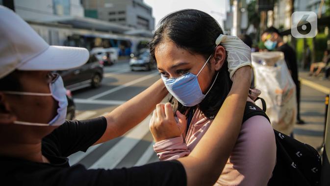 Relawan membagikan masker kepada pejalan kaki di kawasan Bundaran HI, Jakarta, Selasa (17/3/2020). Sebanyak 3.000 masker dibagikan secara gratis sebagai salah satu bentuk keprihatinan sekaligus berpartisipasi dalam upaya mencegah penyebaran virus corona COVID-19. (Liputan6.com/Faizal Fanani)