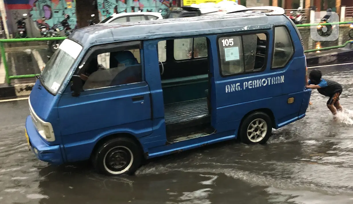 Seorang anak mendorong angkutan umum untuk melintasi banjir yang menggenangi Jalan Arif Rahman Hakim di Depok, Jawa Barat, Senin (18/5/2020). Sistem drainase buruk menjadi penyebab utama kawasan tersebut selalu tergenang banjir setiap hujan deras. (Liputan6.com/Immanuel Antonius)