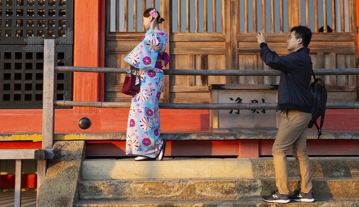 Seorang pria mengambil foto temannya yang mengenakan kimono di kuil Buddha Kiyomizu-dera di Kyoto, Jepang (31/10/2019). Kuil ini adalah situs Warisan Dunia UNESCO dan salah satu tempat wisata paling terkenal di Kyoto. (AP Photo / Aaron Favila)